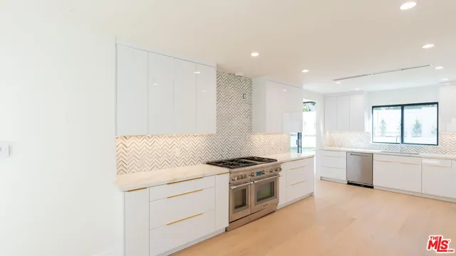 a kitchen with stainless steel appliances a stove a sink and white cabinets