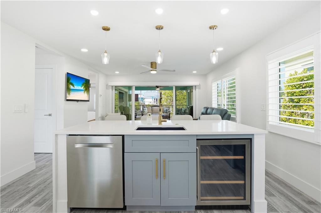 270 Dundee Road Fort Myers Beach, FL 33931 - Photo 9 of 48 Kitchen featuring beverage cooler, dishwasher, an island with sink, open floor plan, and a ceiling fan - Virtually Edited Image