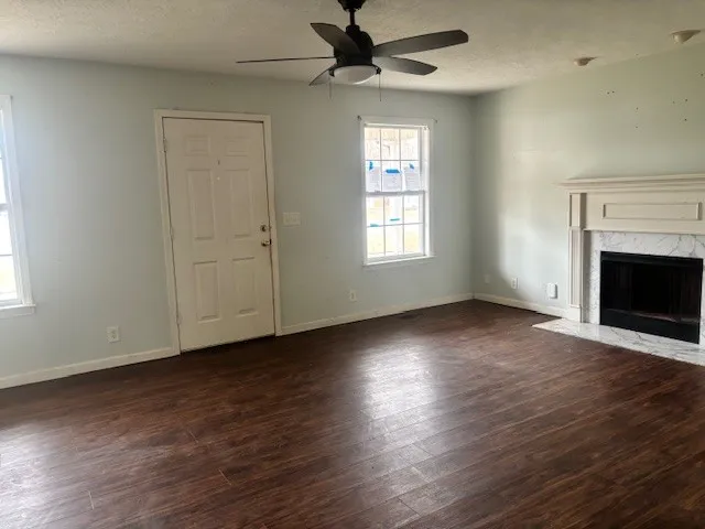 an empty room with wooden floor a ceiling fan and windows