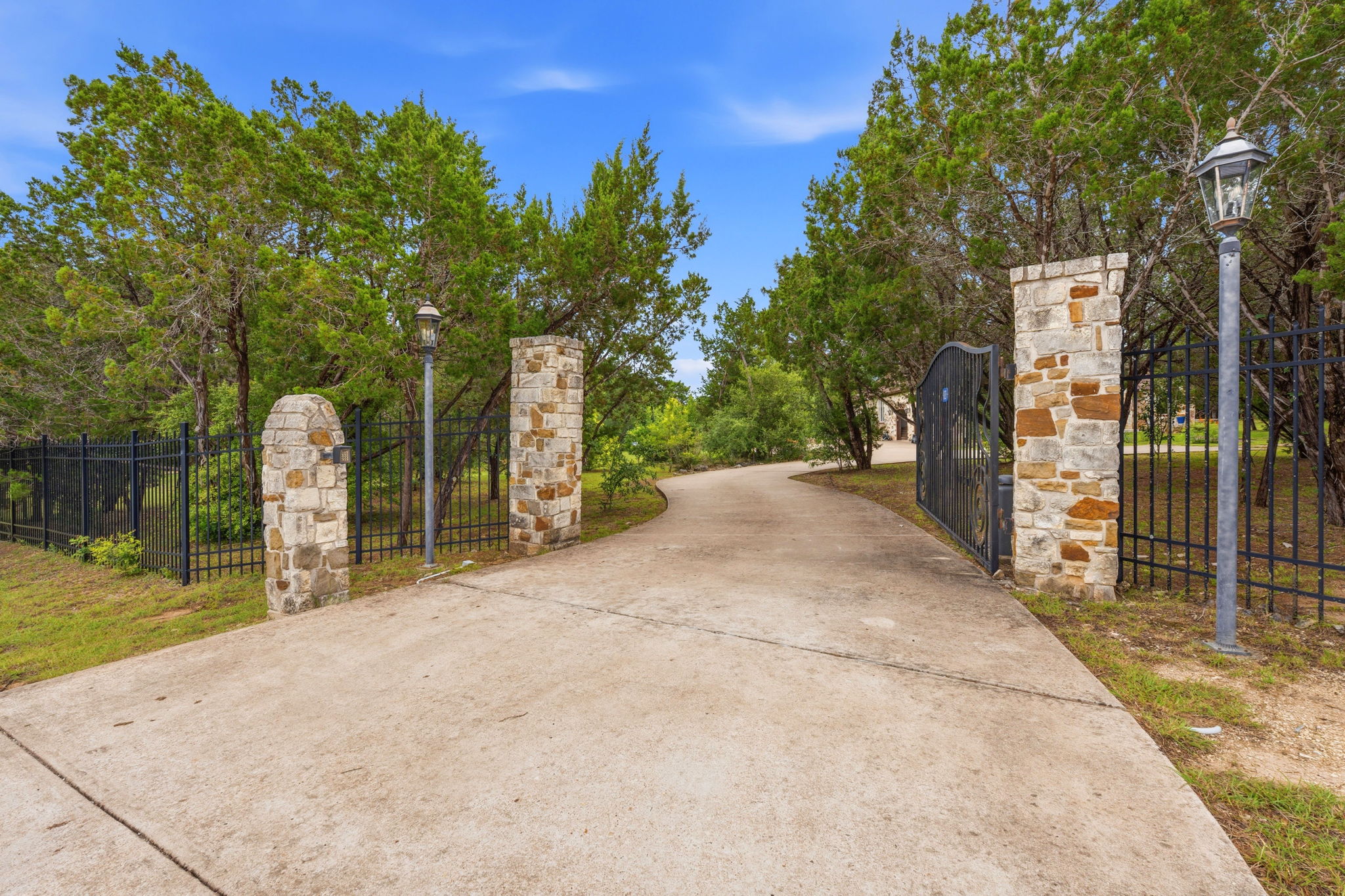 8121 Bluff Trail Austin, TX 78737 - Photo 39 of 40 A long, winding driveway leads through a private, stone-pillared entrance with wrought iron gates, ensuring secluded living.