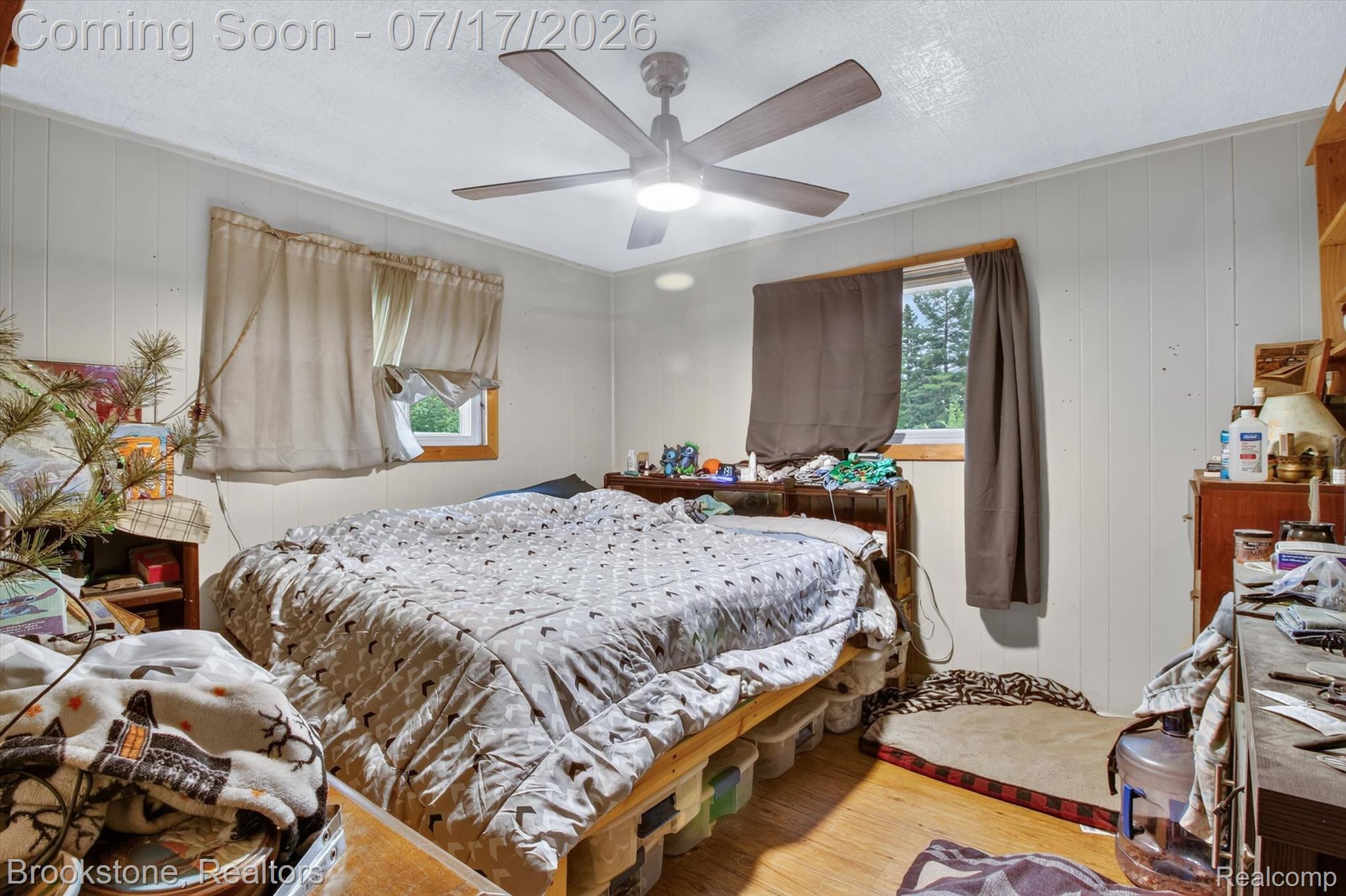 22709 Pleasant Valley Road Hillman, MI 49746 - Photo 19 of 42 Bedroom featuring wood-finish flooring, vertical wall paneling, and a ceiling fan with integrated lighting