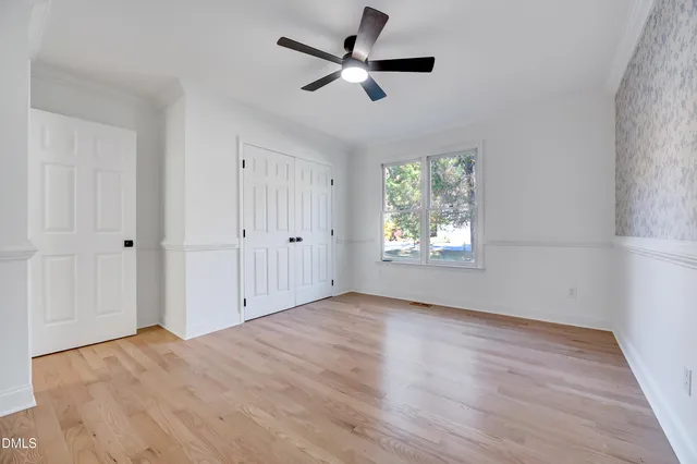 an empty room with wooden floor and a ceiling fan
