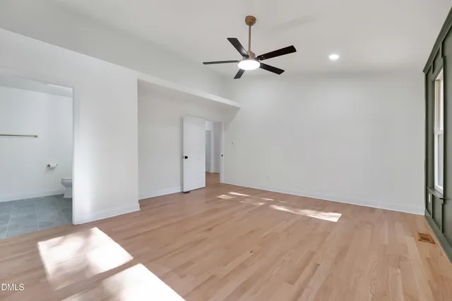 a view of an empty room with a window and a kitchen