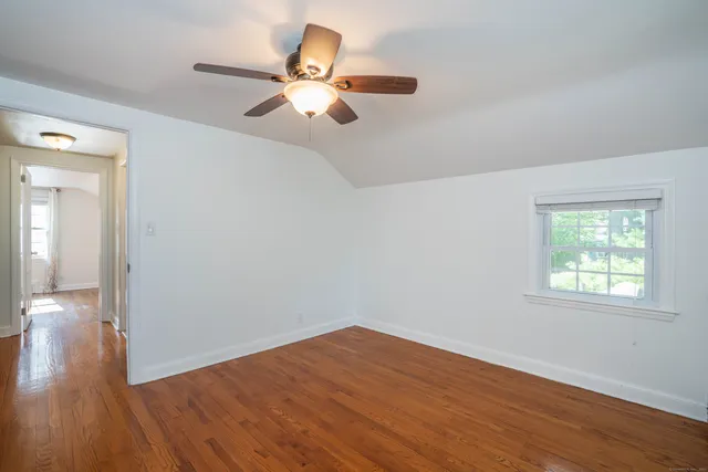 an empty room with wooden floor fan and windows