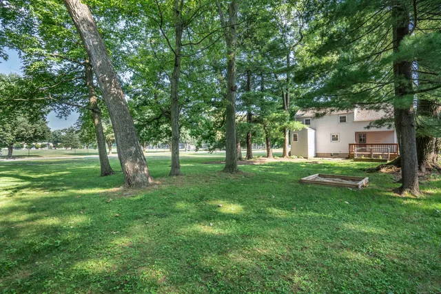 a view of white house with a big yard and large trees