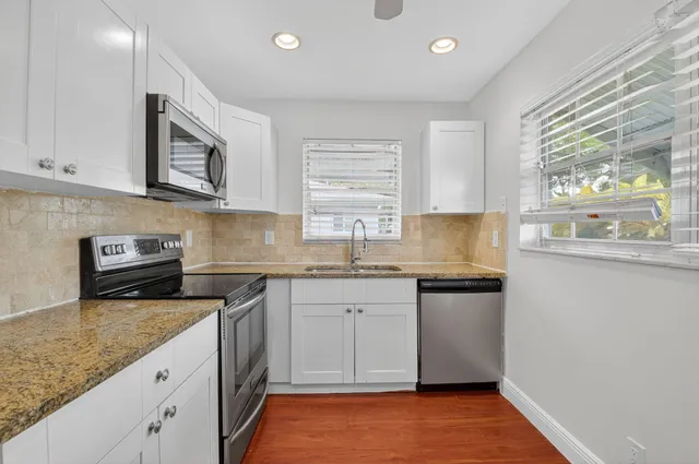 a kitchen with granite countertop cabinets stainless steel appliances a sink and a window
