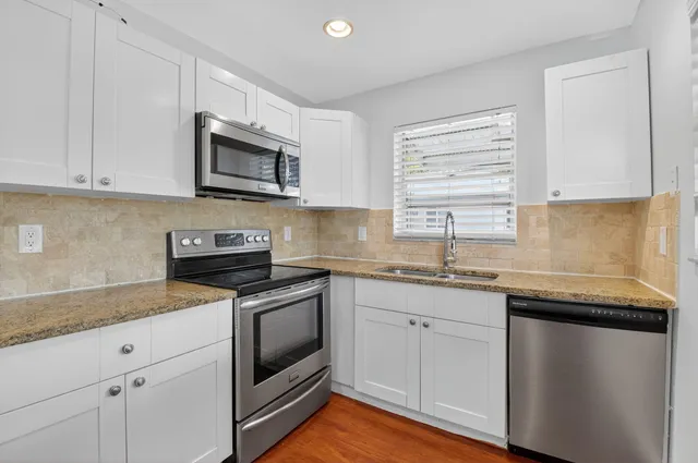 a kitchen with stainless steel appliances granite countertop a sink dishwasher a stove and a microwave oven with cabinets