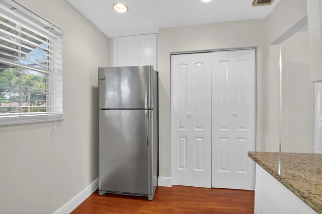 a view of a kitchen with refrigerator and wooden floor