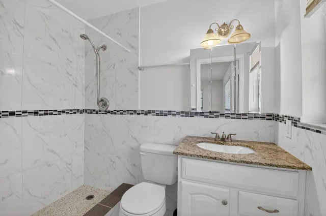 a bathroom with a granite countertop sink a toilet and a mirror