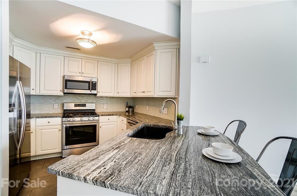 1342 Torrence Circle Davidson, NC 28036 - Photo 9 of 39 a kitchen with granite countertop a stove a sink and a microwave