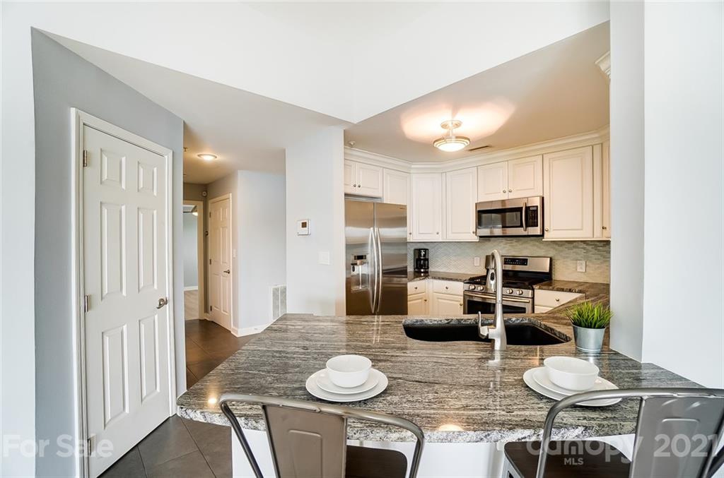 1342 Torrence Circle Davidson, NC 28036 - Photo 10 of 39 a kitchen with stainless steel appliances kitchen island granite countertop a dining table chairs and view living room