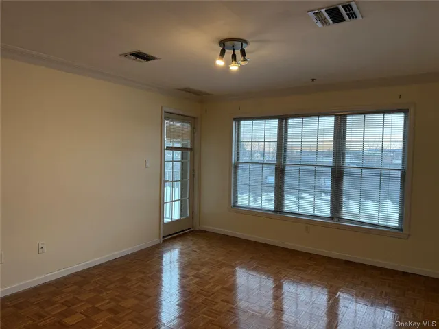a view of an empty room with a window and wooden floor