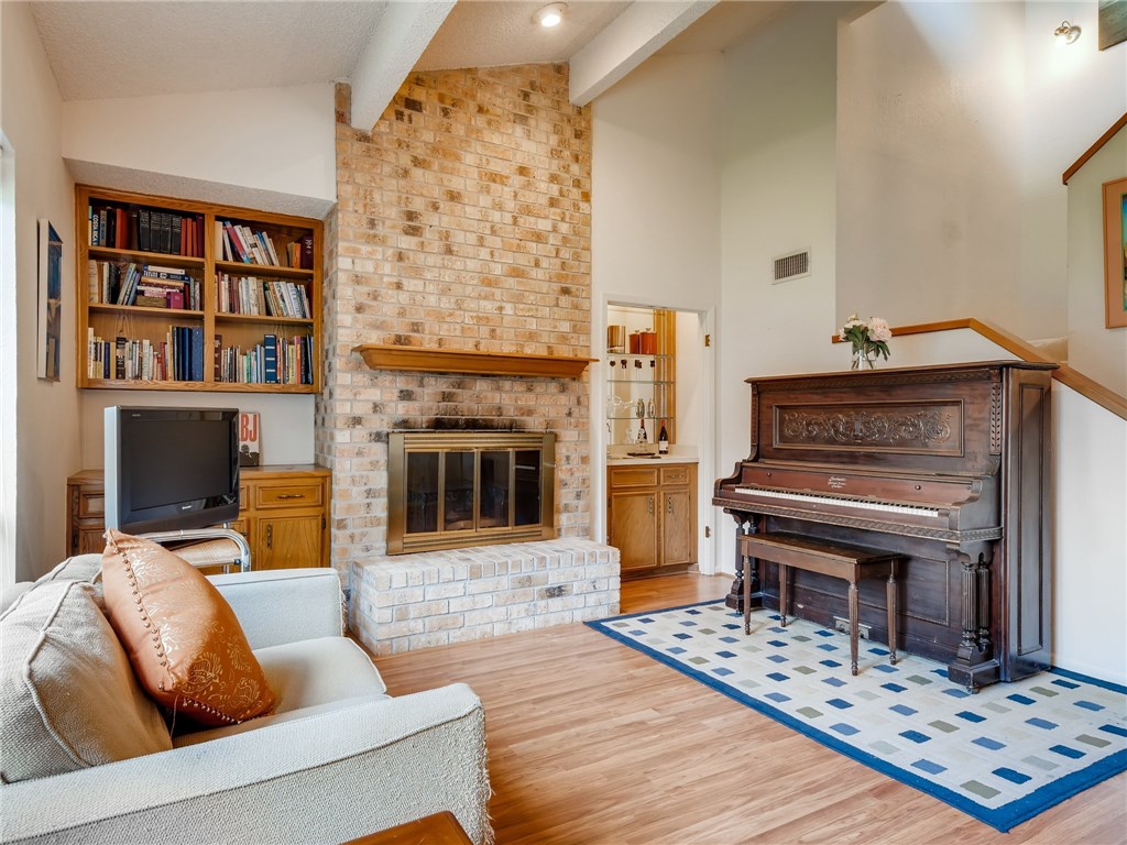 4110 Ridgeline Trail Austin, TX 78731 - Photo 1 of 1 Living room with vaulted beam ceiling, wood-burning brick fireplace, built-in shelves, and wet bar