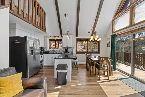 a kitchen with stainless steel appliances granite countertop a sink a stove a refrigerator cabinets and a dining table