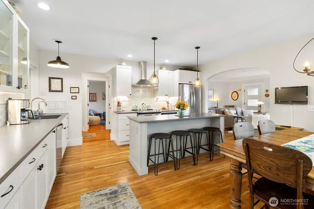 a kitchen with stainless steel appliances kitchen island granite countertop a table chairs and a refrigerator