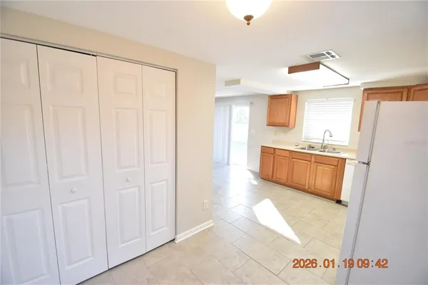 a view of kitchen with stainless steel appliances granite countertop a refrigerator a sink and white cabinets