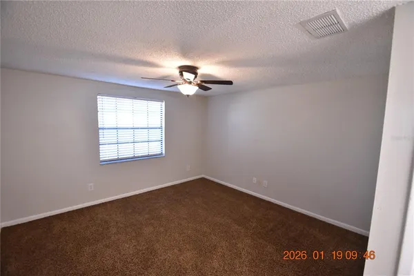 an empty room with windows and fan