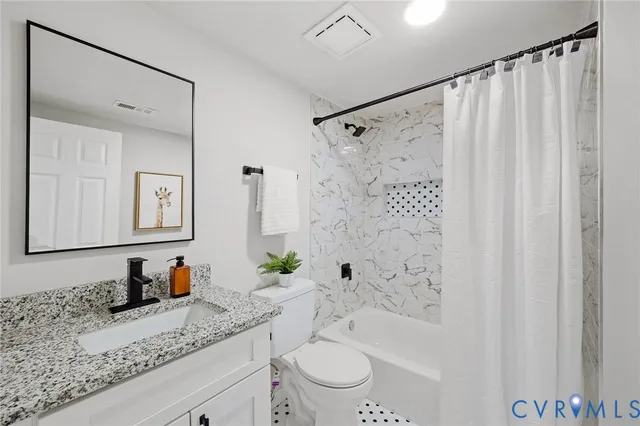 a bathroom with a granite countertop sink a toilet and shower
