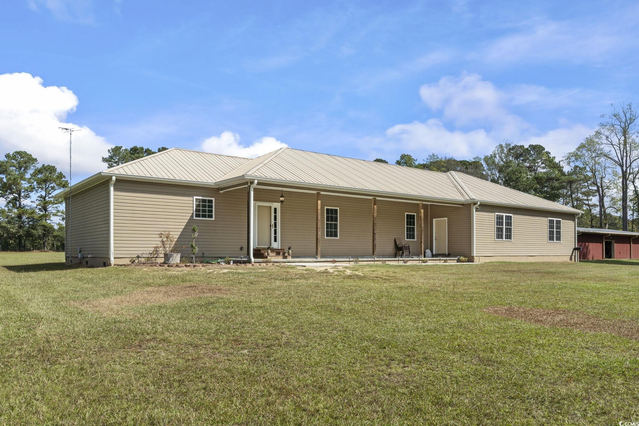 Rear view of house with a lawn, a metal roof, and a patio
