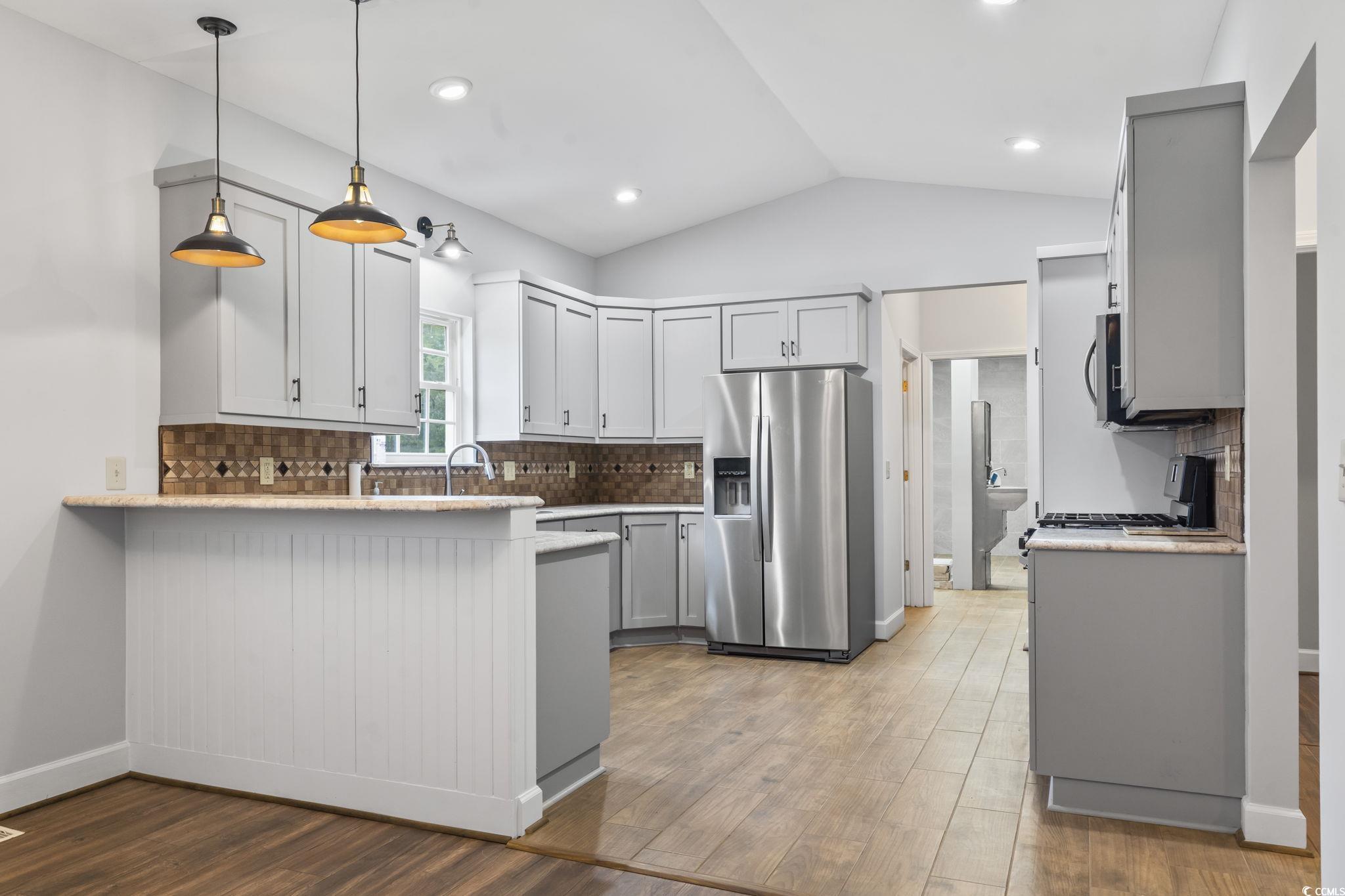 1585 Daisy Road Loris, SC 29569 - Photo 13 of 39 Kitchen with decorative backsplash, pendant lighting, appliances with stainless steel finishes, light wood finished floors, and lofted ceiling