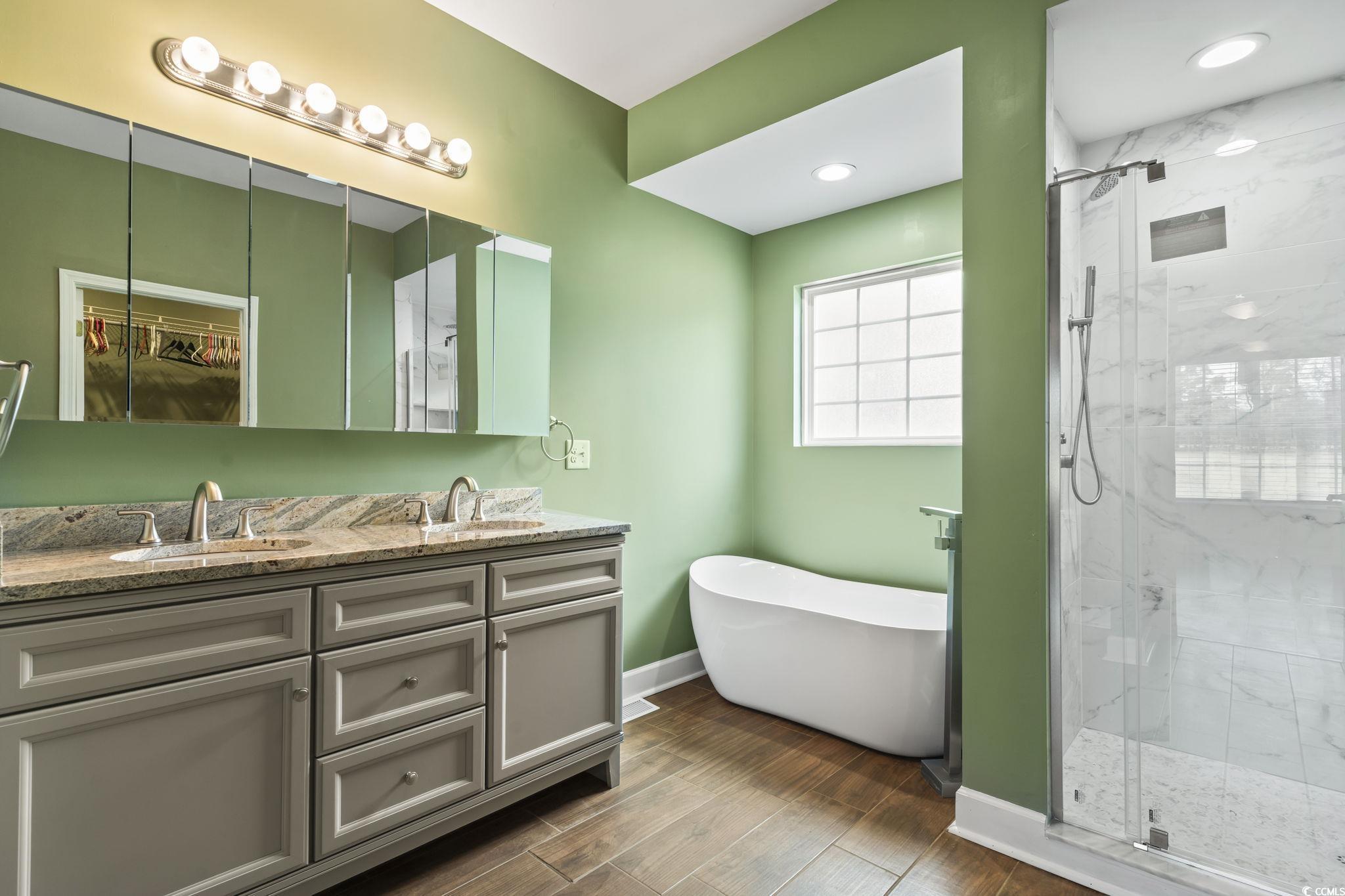 1585 Daisy Road Loris, SC 29569 - Photo 17 of 39 Bathroom featuring a freestanding tub, a marble finish shower, double vanity, and dark wood-style flooring
