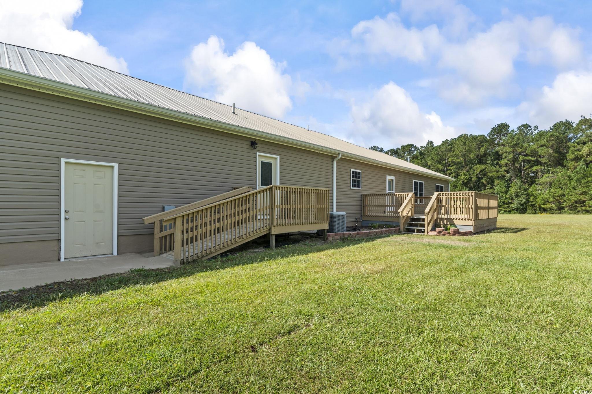 1585 Daisy Road Loris, SC 29569 - Photo 3 of 39 Rear view of house featuring a yard, a wooden deck, a metal roof, and a patio