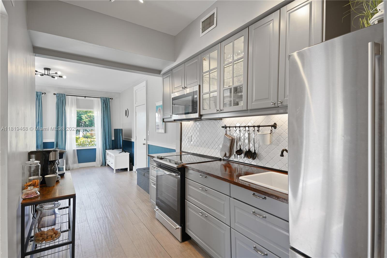 1753 Southwest 13th Street, Unit 1 Miami, FL 33145 - Photo 2 of 13 a kitchen with granite countertop a refrigerator a sink and wooden floors