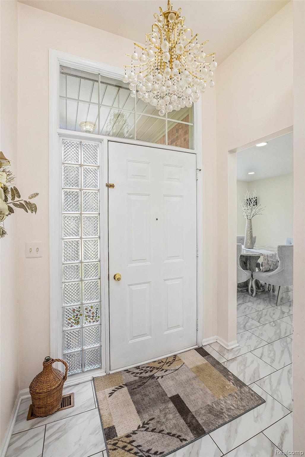 5477 Victory Circle Sterling Heights, MI 48310 - Photo 5 of 32 Entryway featuring a crystal chandelier, a solid white entry door, a glass block sidelight, a transom window, and large format tiled flooring