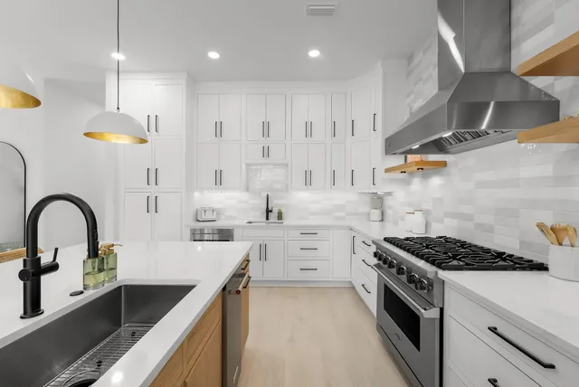 a living room with couches and kitchen view with wooden floor