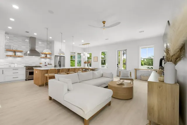 a view of a hallway to a livingroom with wooden floor and stairs