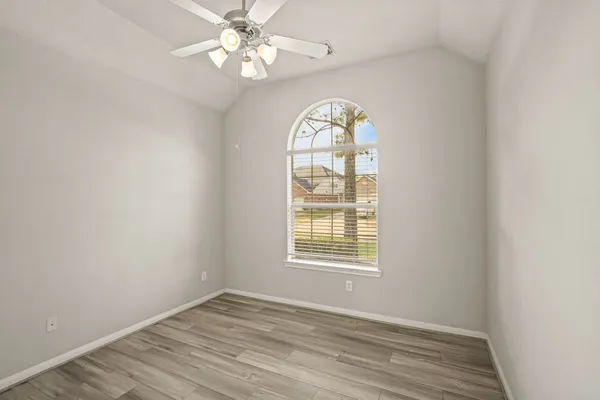 an empty room with wooden floor chandelier fan and window