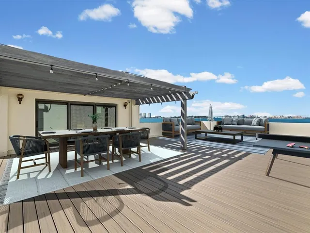 a roof deck view with dining table and chairs with wooden floor