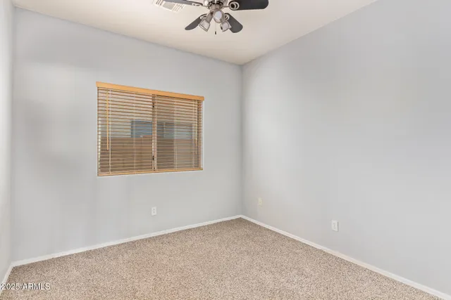 an empty room with a window and a ceiling fan