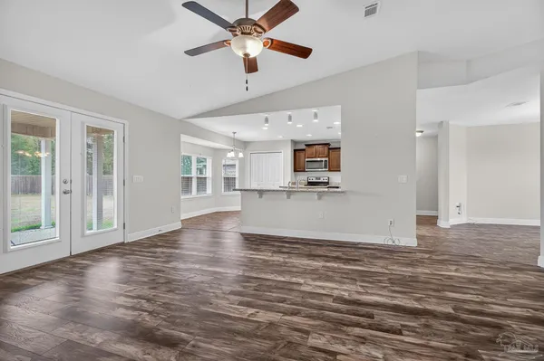 a view of empty room with wooden floor and fan
