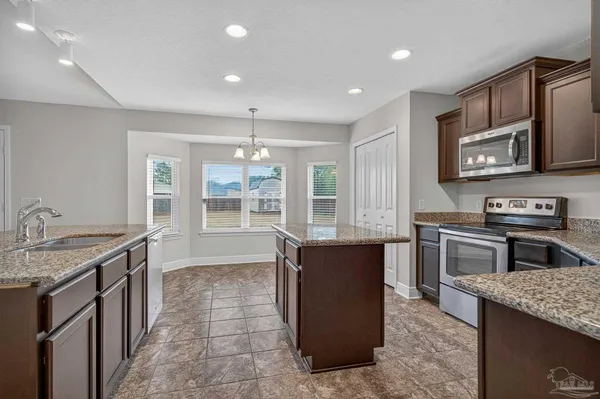 a kitchen with stainless steel appliances granite countertop a stove a sink and a microwave