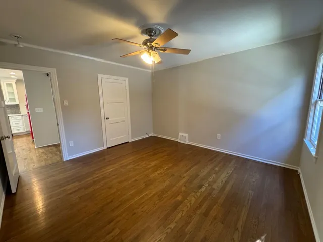 an empty room with wooden floor and chandelier fan