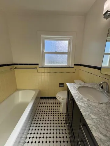 a bathroom with a granite countertop sink a toilet a mirror and shower