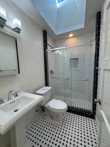 a bathroom with a sink a toilet a mirror and shower