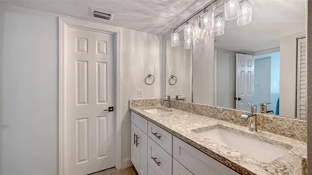 a bathroom with a granite countertop double vanity sink and a mirror