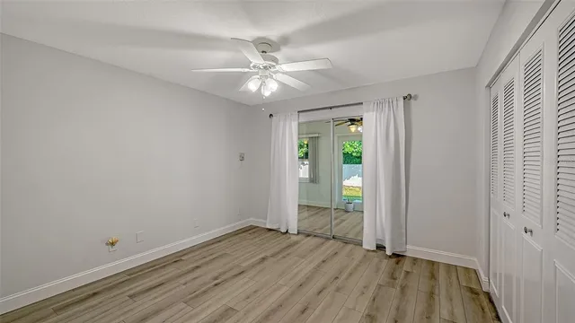 an empty room with wooden floor fan and windows