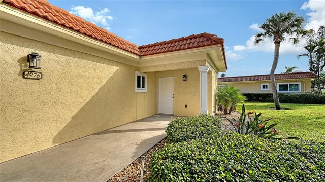 a sign board with flower plants and wooden fence