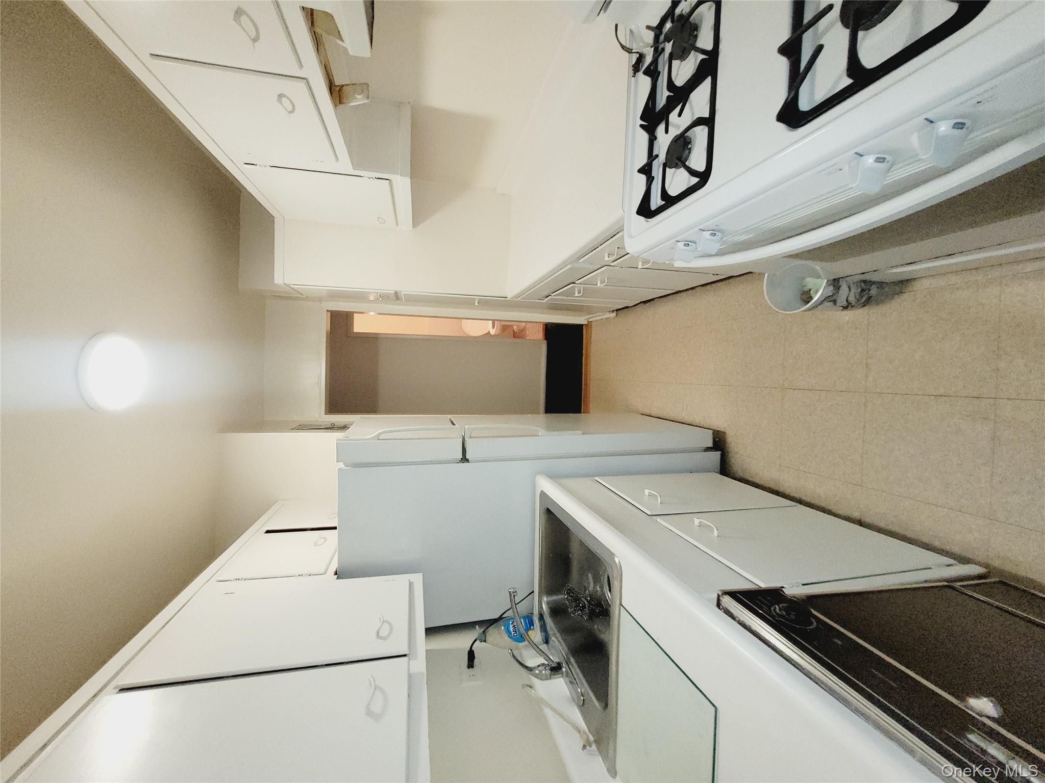 99-30 59th Avenue, Unit 3K Queens, NY 11368 - Photo 5 of 21 a kitchen with a refrigerator and white cabinets