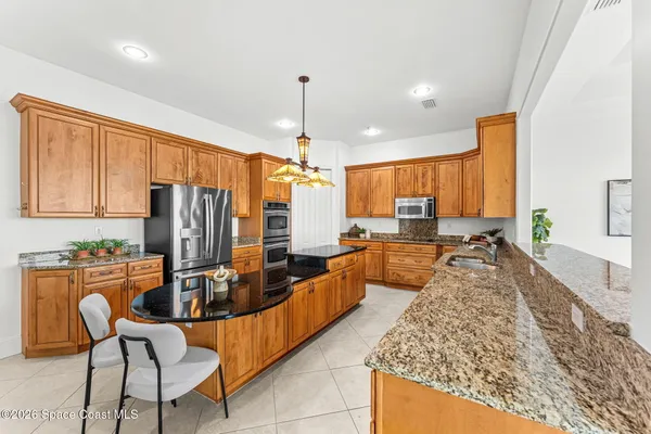 a large kitchen with kitchen island granite countertop a counter space dining table and stainless steel appliances