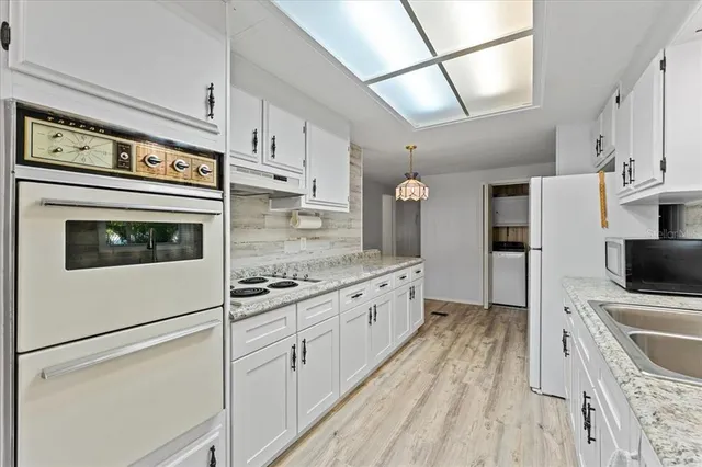 a kitchen with granite countertop white cabinets and white appliances
