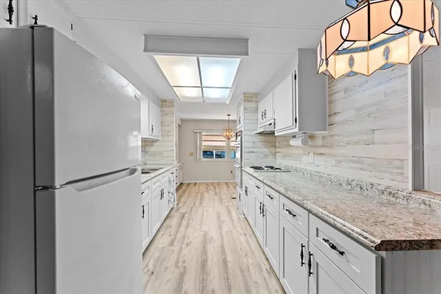 a kitchen with granite countertop white cabinets and white appliances