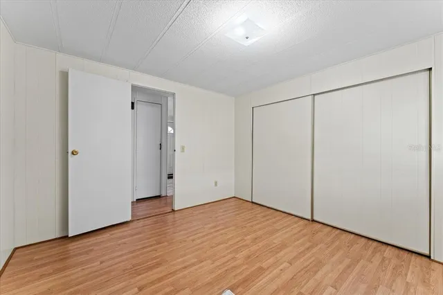 a view of an empty room with wooden floor and closet
