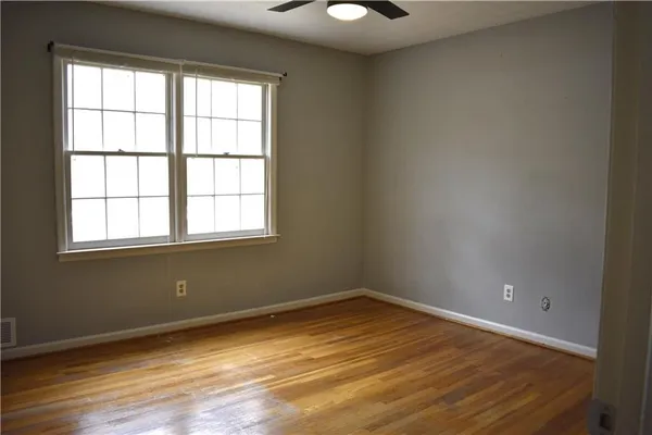 an empty room with wooden floor and windows