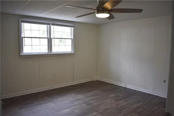 an empty room with wooden floor ceiling fan and windows