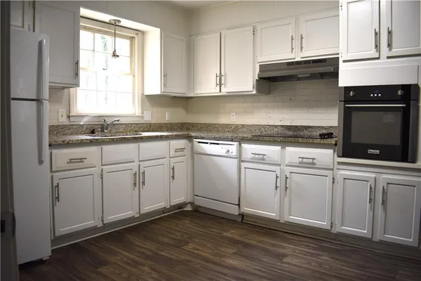a kitchen with white cabinets granite counter tops and a stove