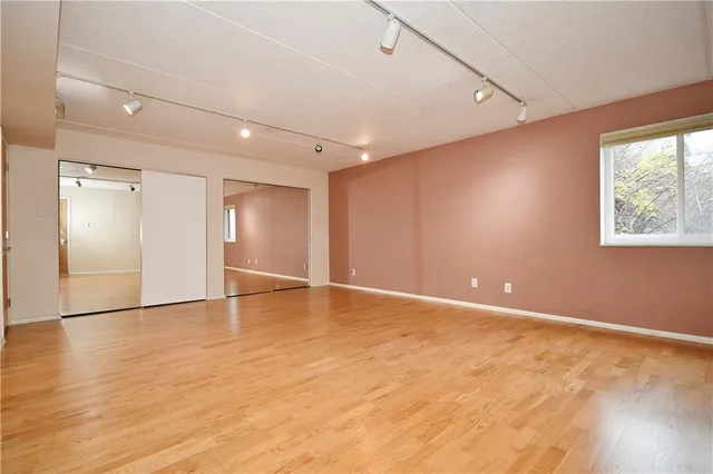 an empty room with wooden floor and windows